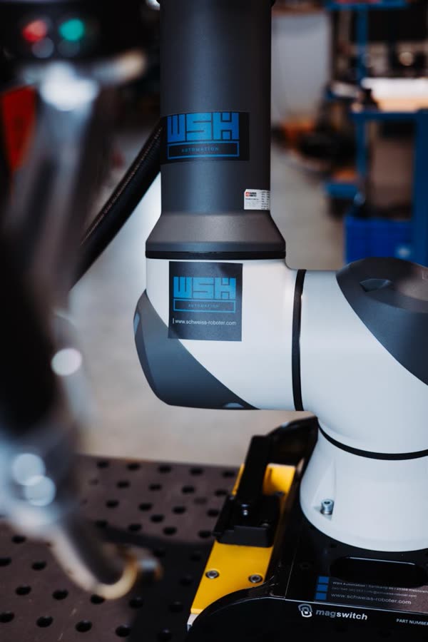 Cobot auf einer gelben Magnetbasis auf dem Lochtisch