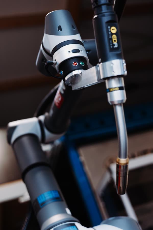 Schweißbrenner am Handgelenk des Cobots über dem Bauteil