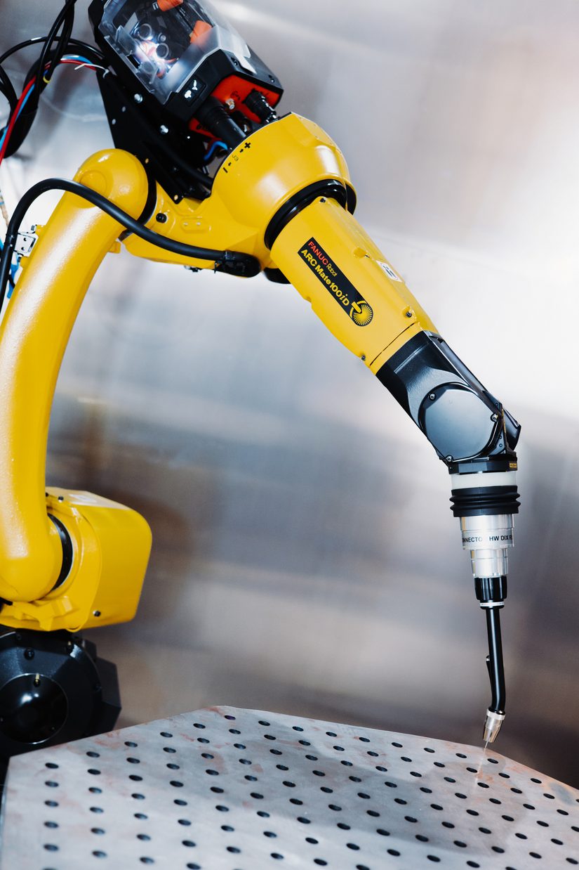 Fanuc ArcMate 100iD Schweißroboter mit Brenner über dem Schweißtisch