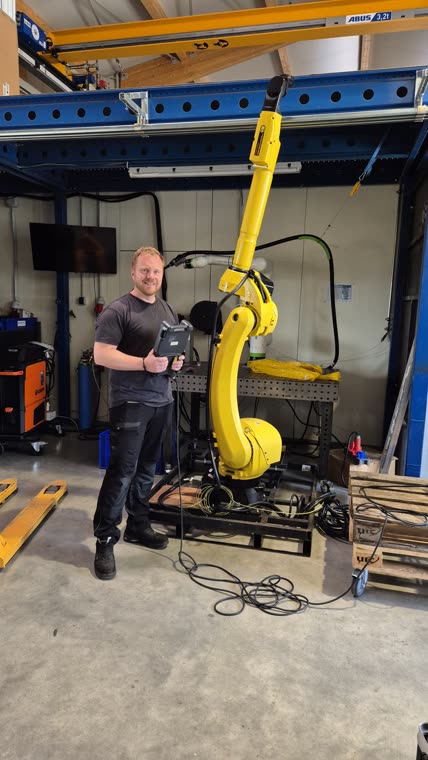 Mitarbeiter von WSH Automation vor dem FANUC Roboter mit Bediengerät