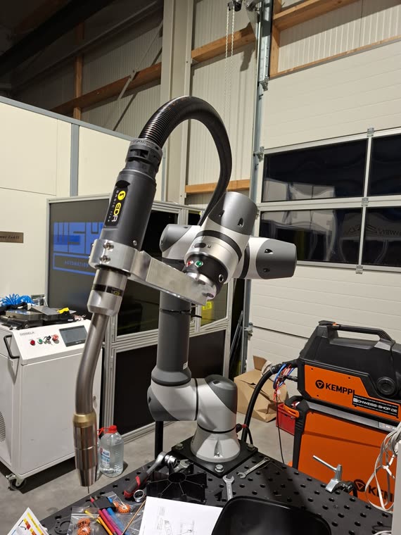 Roboterarm mit Schweißbrenner, im Hintergrund Laserquelle und Kemppi Stromquelle